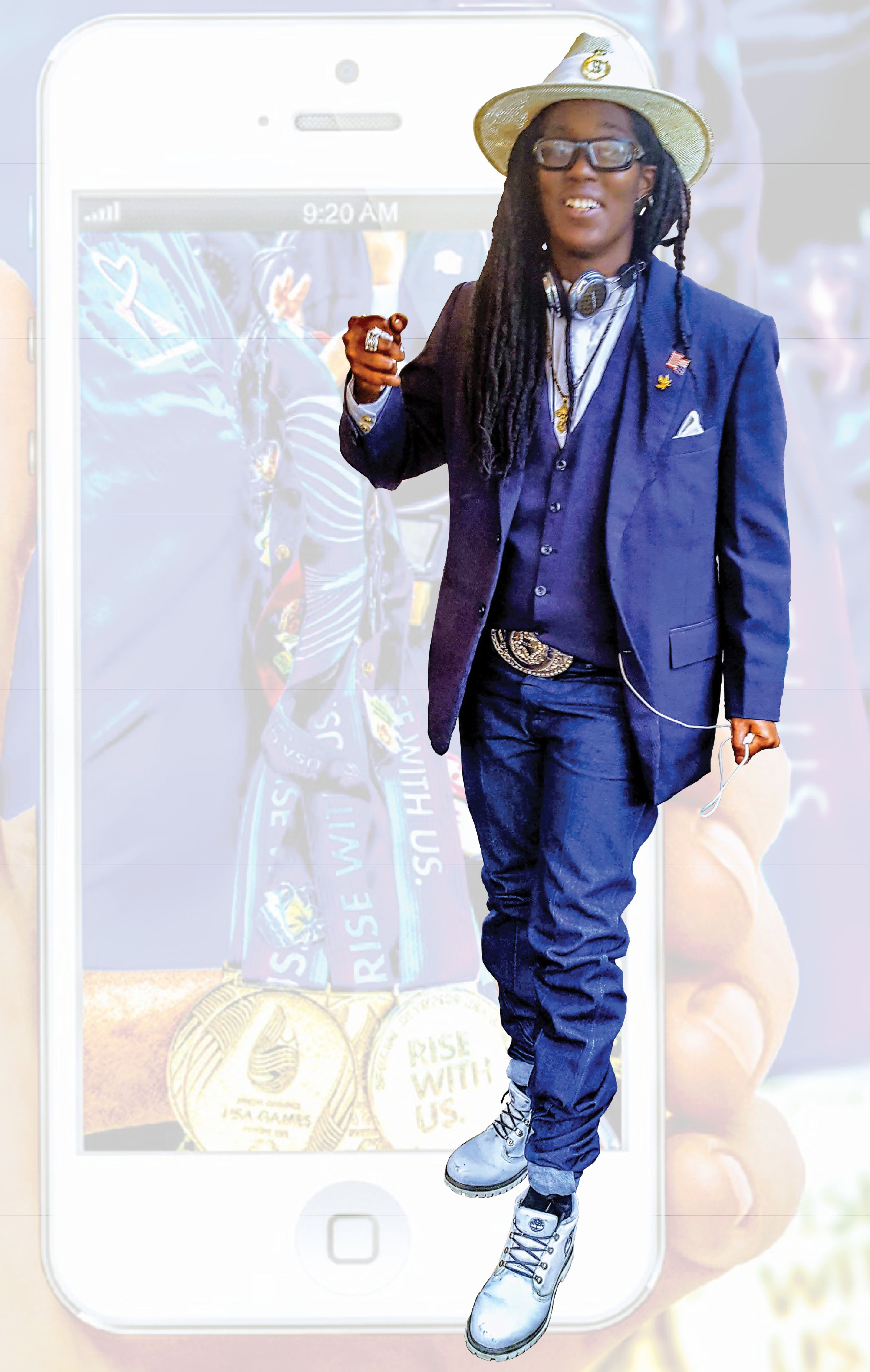 Smiling Ashton Smith, with long black dreds, emphasizing a point with his right hand, wearing a royal blue suit and vest, white shirt, white hat, large silver belt buckle, and headphones.